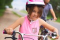 Portrait of a litte girl in a pink safety helmet driving her bike.