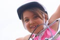 Portrait of a litte Cacasian girl in a pink safety helmet driving her bike.