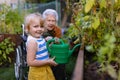 Portrait of a little adorable girl helping her grandmother in the garden, watering plants, takes care of vegetables