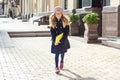 Portrait of little adorable schoolgirl with notebooks and backpack running to school, girl wearing glasses cap, urban style backgr Royalty Free Stock Photo