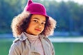 Portrait of a little African-American girl in a red hat in a park against the background of a lake on a sunny day Royalty Free Stock Photo
