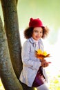 Portrait of a little African-American girl in a red hat in a park against the background of a lake on a sunny day. A girl is Royalty Free Stock Photo