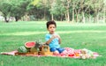 Portrait of little african curly hair cute boy playing, eating piece of watermelon with happiness while sitting on the green field Royalty Free Stock Photo