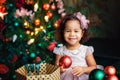 Portrait of a little African girl on the background of a decorated Christmas tree. The child is holding a ball in his hands Royalty Free Stock Photo