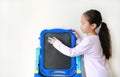 Portrait of little asian child girl erasing on black board over white background. Education concept
