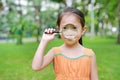 Portrait little Asian child girl looking through magnifying glass on park garden Royalty Free Stock Photo