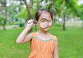 Portrait little Asian child girl looking through magnifying glass on park garden Royalty Free Stock Photo