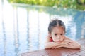 Portrait of little Asian child girl in a mermaid suit sitting and lying poolside with looking camera