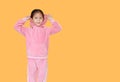 Portrait of little Asian child girl in pink tracksuit or sport cloth with putting hood on head isolated on orange background with Royalty Free Stock Photo