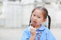 Portrait of little Asian child girl in school uniform enjoy eating tasty chocolate vanilla ice cream