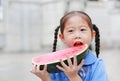 Portrait of little Asian child girl in school uniform enjoy eating tasty watermelon Royalty Free Stock Photo