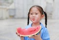 Portrait of little Asian child girl in school uniform enjoy eating tasty watermelon Royalty Free Stock Photo