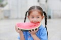 Portrait of little Asian child girl in school uniform enjoy eating tasty watermelon Royalty Free Stock Photo
