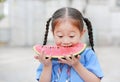 Portrait of little Asian child girl in school uniform enjoy eating tasty watermelon Royalty Free Stock Photo