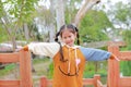 Portrait of little Asian child girl in warm clothes open arms standing on balcony in the garden Royalty Free Stock Photo