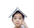 Portrait of little Asian child thinking and put a book on top Royalty Free Stock Photo