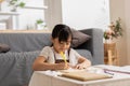 Portrait of little Asian girl child study learn at home smile and happiness.Cute girl drawing and handwriting in notebook to