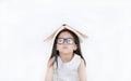 Portrait of little Asian girl place hardcover book on her head and looking camera over white background Royalty Free Stock Photo