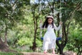 Portrait of little Asian girl playing the swing under the big tree in the nature forest select focus shallow depth of field Royalty Free Stock Photo