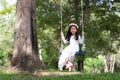 Portrait of little Asian girl playing the swing under the big tree in the nature forest with soft tone processed Royalty Free Stock Photo