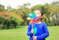 Portrait of little Asian kid girl blowing wind turbine in the summer garden Royalty Free Stock Photo