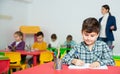 Portrait of little assiduous boy with pen and notebook at lesson in elementary school Royalty Free Stock Photo