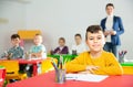 Portrait of little assiduous boy with pen and notebook at lesson in elementary school Royalty Free Stock Photo