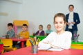 Portrait of little assiduous girl with pen and notebook at lesson in elementary school Royalty Free Stock Photo
