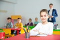 Portrait of little assiduous girl with pen and notebook at lesson in elementary school Royalty Free Stock Photo