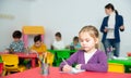 Portrait of little assiduous girl with pen and notebook at lesson in elementary school Royalty Free Stock Photo