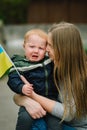 Portrait little baby boy crying and calls to Stop war in Ukraine raises yellow and blue flag Ukraine. No war, stop russian Royalty Free Stock Photo