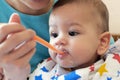 Portrait of little baby boy eating food. Baby with a spoon in feeding chair. Cute baby eating first meal