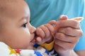 Portrait of little baby boy eating food. Baby with a spoon in feeding chair. Cute baby eating first meal