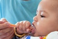 Portrait of little baby boy eating food. Baby with a spoon in feeding chair. Cute baby eating first meal