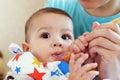 Portrait of little baby boy eating food. Baby with a spoon in feeding chair. Cute baby eating first meal