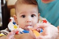 Portrait of little baby boy eating food. Baby with a spoon in feeding chair. Cute baby eating first meal