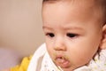 Portrait of little baby boy eating food. Baby with a spoon in feeding chair. Cute baby eating first meal