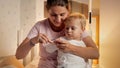 Portrait of little baby boy looking at mother cutting off his fingernails before going to sleep in bed Royalty Free Stock Photo