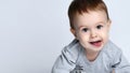 Portrait of little baby boy toddler in grey casual jumpsuit lying on floor, looking at camera and smiling over white background Royalty Free Stock Photo