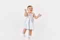 Portrait of little baby girl, toddler in beautiful dress walking, smiling and clapping hands against white studio Royalty Free Stock Photo