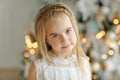 Portrait of little beautiful blond girl, Christmas tree lights i Royalty Free Stock Photo