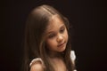 Portrait of a little beautiful girl with long hair against a dark background