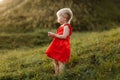 Portrait of a little beautiful girl in red dress on nature on summer day vacation. The playing in the park at the sunset time. Royalty Free Stock Photo