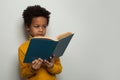 Portrait of little black child boy reading a book on white background Royalty Free Stock Photo