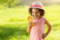 Portrait of little Black girl drinking orange juice in a glass with straw at outdoor park. Smiling Child in summer hat Royalty Free Stock Photo