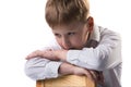 Portrait of little blond boy in white shirt leaning on the chair