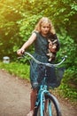 Portrait of a little blonde girl in a casual dress, holds cute spitz dog, in a park. Royalty Free Stock Photo