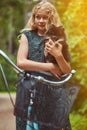 Portrait of a little blonde girl in a casual dress, holds cute spitz dog, in a park. Royalty Free Stock Photo