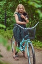 Portrait of a little blonde girl in a casual dress, holds cute spitz dog, in a park. Royalty Free Stock Photo