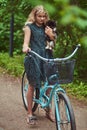 Portrait of a little blonde girl in a casual dress, holds cute spitz dog, in a park. Royalty Free Stock Photo